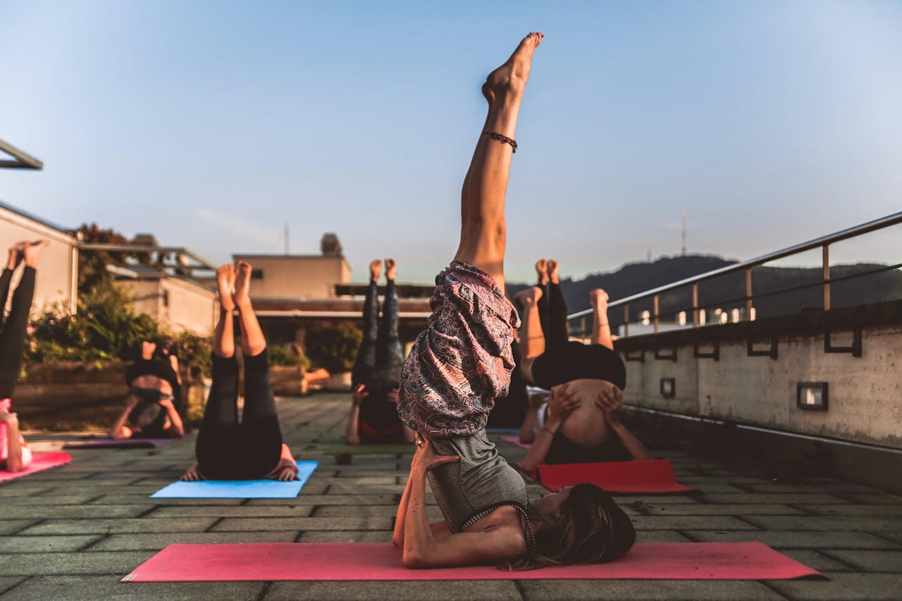 service-06 People practicing yoga on mats outdoors during sunset, focusing on wellness.