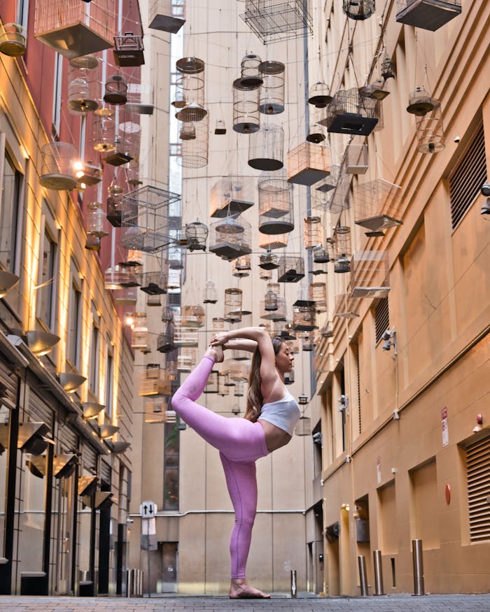 service-02 Woman performing a yoga pose in Angel Place, Sydney, surrounded by hanging birdcages.