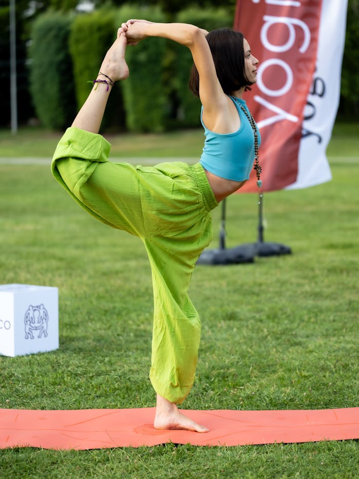 our-mission Woman performing a yoga pose outdoors on a mat with yoga banner and trees.